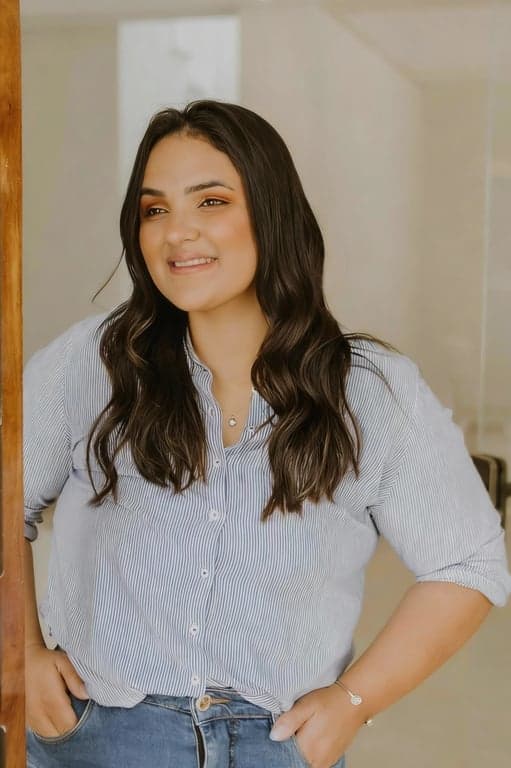 a portrait of a person with a clearly slimmer chin created by compressing under-chin fullness and smoothing excess volume while maintaining jawline geometry; reinforce a clean neckline silhouette; preserve facial identity, skin pores, and natural shading; avoid plastic skin effects; do not modify background; the face should read noticeably leaner in the lower region