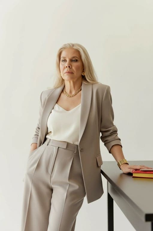 a portrait of a person wearing a Korean-style tailored blazer with softly structured shoulders, relaxed straight cut, matte fabric texture, paired with high-waist trousers, clean proportions, calm posture, soft neutral lighting