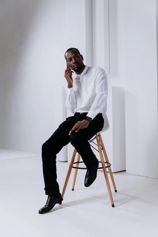 a portrait of a man in a flannel plaid shirt and jeans, holding a hot drink at a lively fall fair with string lights