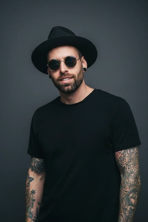 A realistic edited portrait of a man, detailed skin retouching that preserves pores and texture, natural teeth whitening, subtle eye enhancement, realistic color grading, studio backdrop.