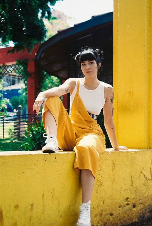 age ai generator before photo - woman sitting on the yellow wall