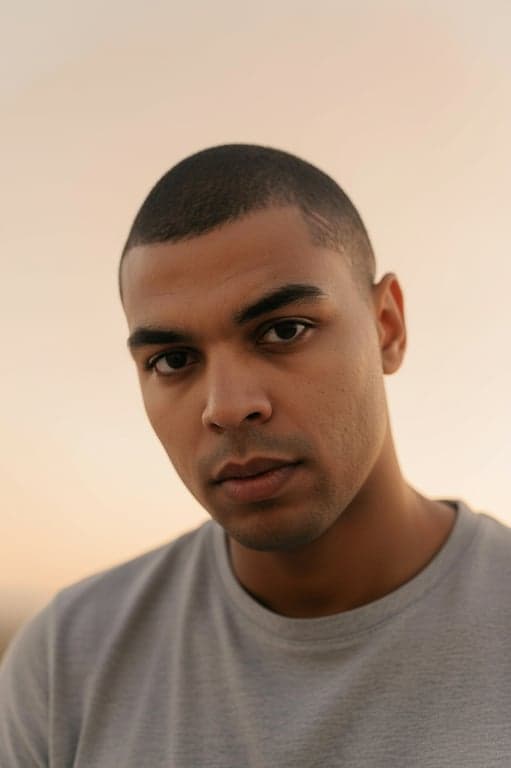 a portrait of a person edited to preserve soft, even face lighting, while removing irregular lens flare, harsh light streaks, and distracting shadow artifacts that interfere with facial readability