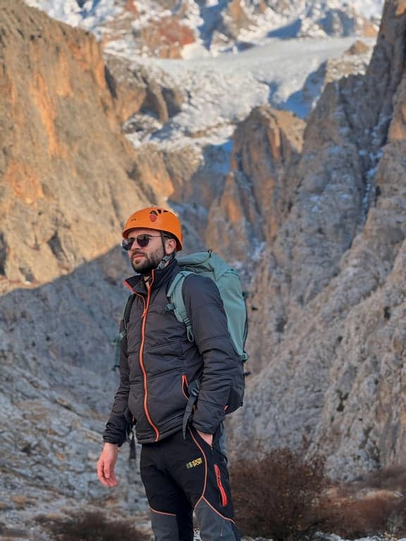 create a dating-ready profile photo by correcting camera angle to eye level, improving posture to appear open and confident, redesigning lighting to remove harsh facial shadows, enhancing eye visibility, sharpening facial detail while preserving skin texture, simplifying the background, and ensuring the result looks clearly more flattering and intentional than the original casual photo