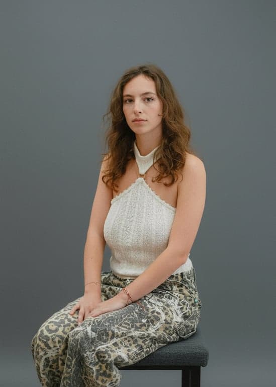 A formal corporate or yearbook portrait style, characterized by even, flat frontal lighting, a medium grey backdrop, and a serious, confident expression directed at the viewer.