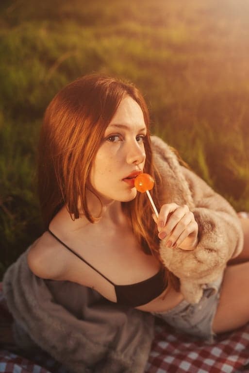 a portrait of a woman in an ordinary setting edited to have golden hour sunlight, with long shadows, warm orange tones, and a soft hazy glow from the side.