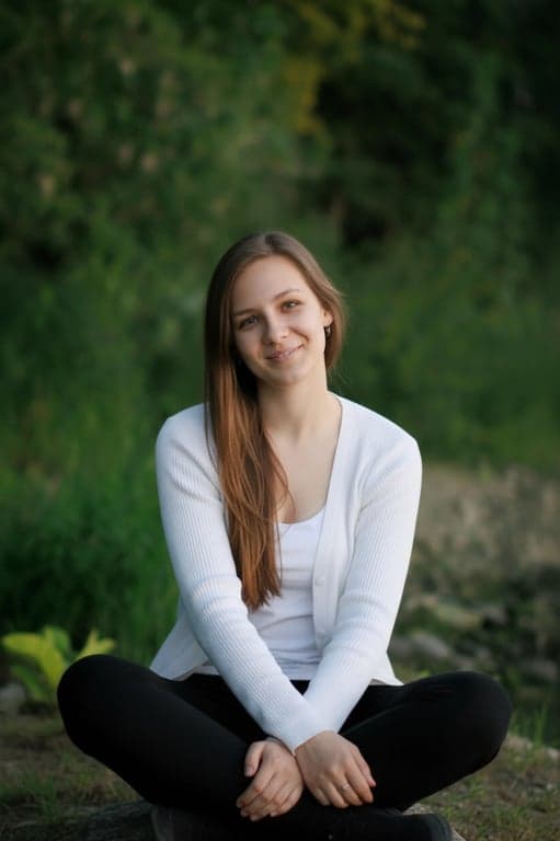 a portrait of a person edited to replace the original posture with a clearly more expressive and relaxed pose, such as standing tall with open shoulders or sitting with crossed legs and upright torso; maintain realistic anatomy; avoid stiffness; do not alter background