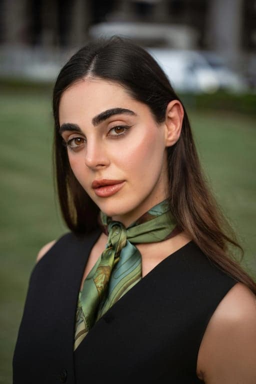 A fashion portrait emulating 70s magazine photography, with bold makeup, textured hair, a simple studio backdrop, and colors leaning towards sepia and magenta.