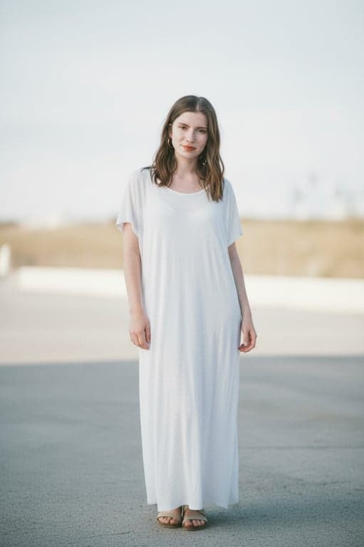 Extend the original portrait of the woman to a full-body image while preserving her identity, facial features, clothing style, and background. Naturally reconstruct the missing lower body with realistic human proportions, consistent posture, and seamless continuity in lighting, fabric texture, and body alignment so the result looks like the original photo was taken full-body.