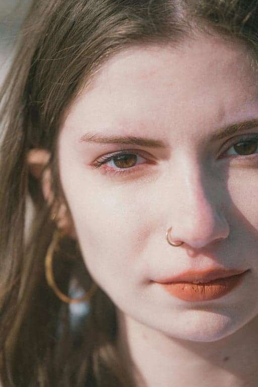 Extend the original portrait of the woman to a full-body image while preserving her identity, facial features, clothing style, and background. Naturally reconstruct the missing lower body with realistic human proportions, consistent posture, and seamless continuity in lighting, fabric texture, and body alignment so the result looks like the original photo was taken full-body.