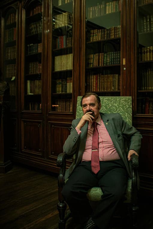 a portrait of a person transformed by lowering the hairline substantially, adding hair coverage to the forehead so the head shape looks fuller and the facial proportions appear smaller