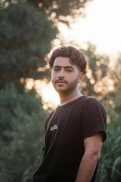 a portrait of a man edited in a Korean wavy perm hairstyle style, so that the top hair has large loose waves forming visible curls typical of Korean men perm looks, while the sides and back are short and straight, with curl texture appearing only on the top section, and unchanged face and original lighting